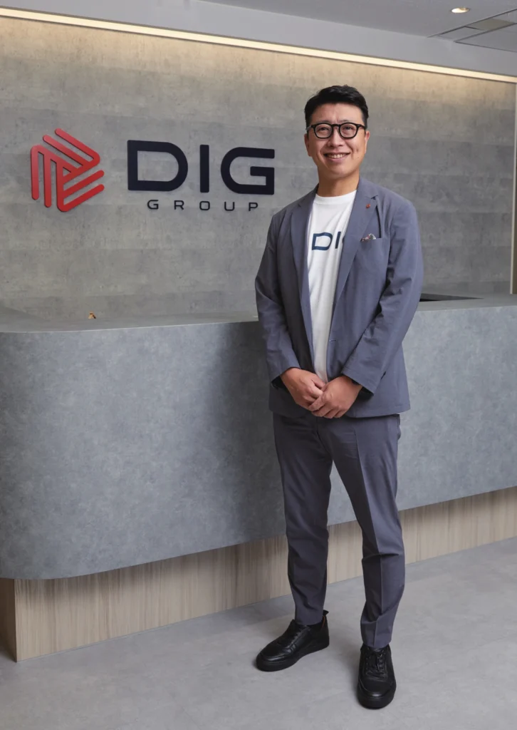 DIGグループのロゴの前に立つ小西慎太郎氏