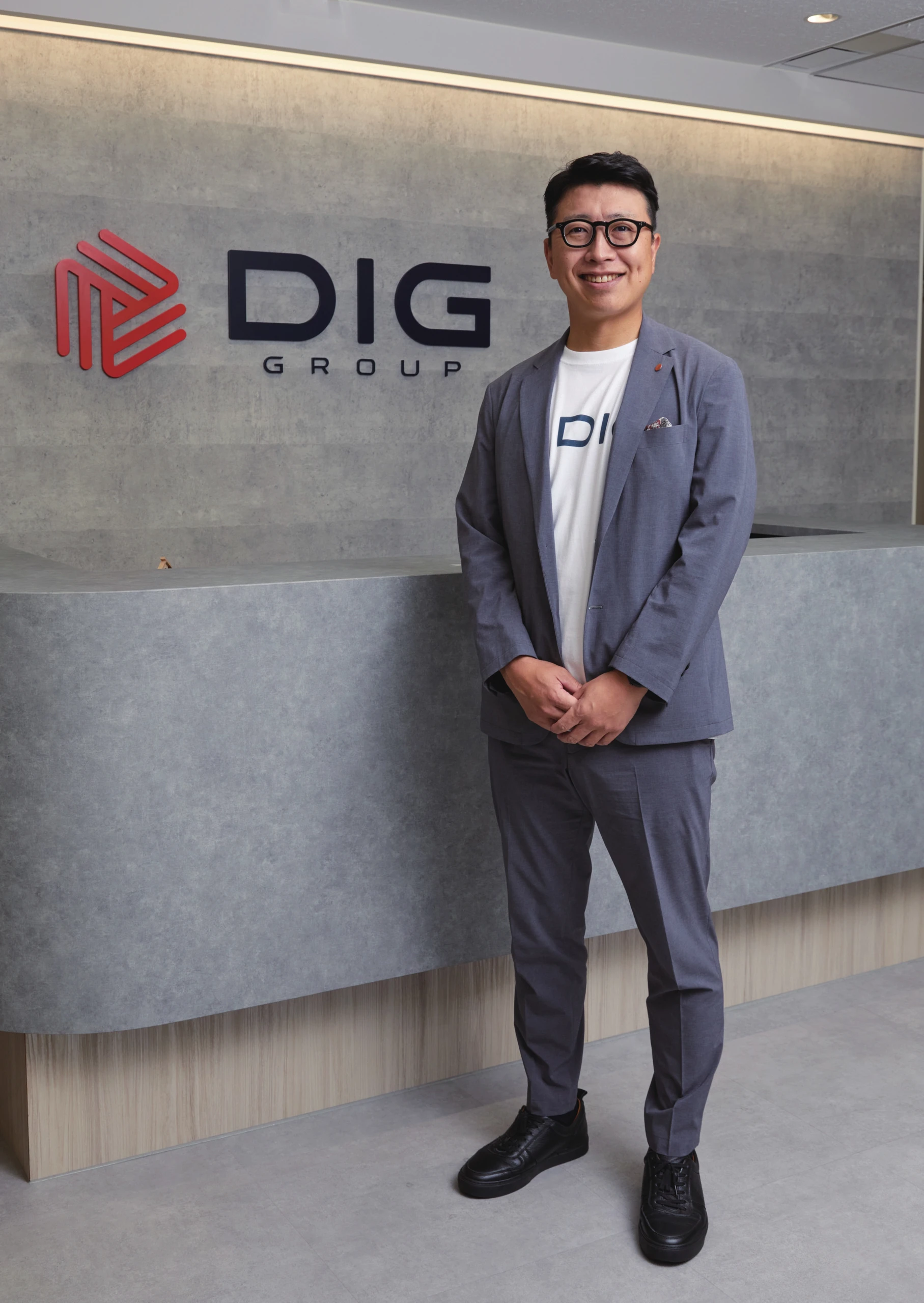DIGグループのロゴの前に立つ小西慎太郎氏