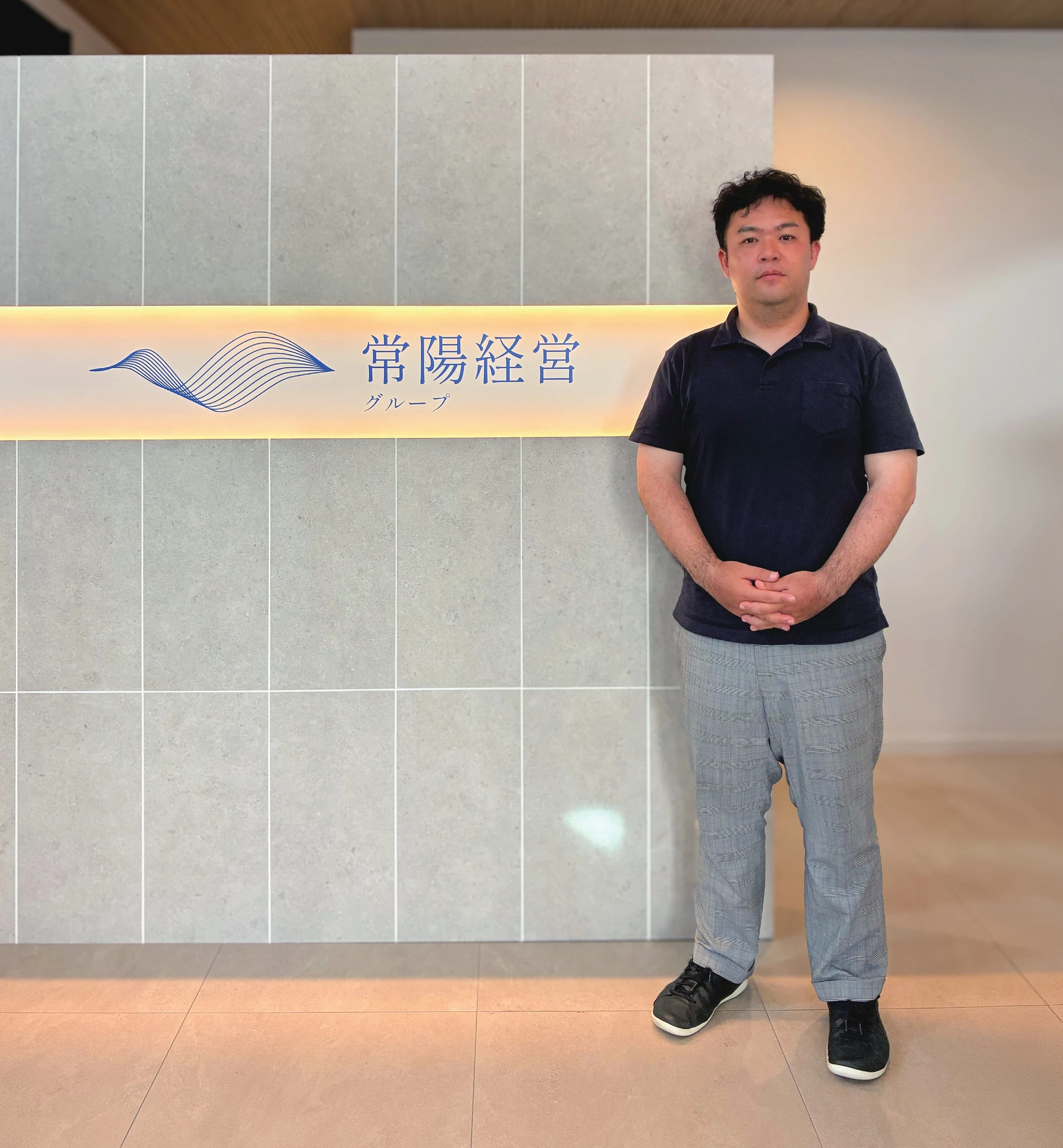 常陽経営グループのロゴの前に立つ西原亮氏